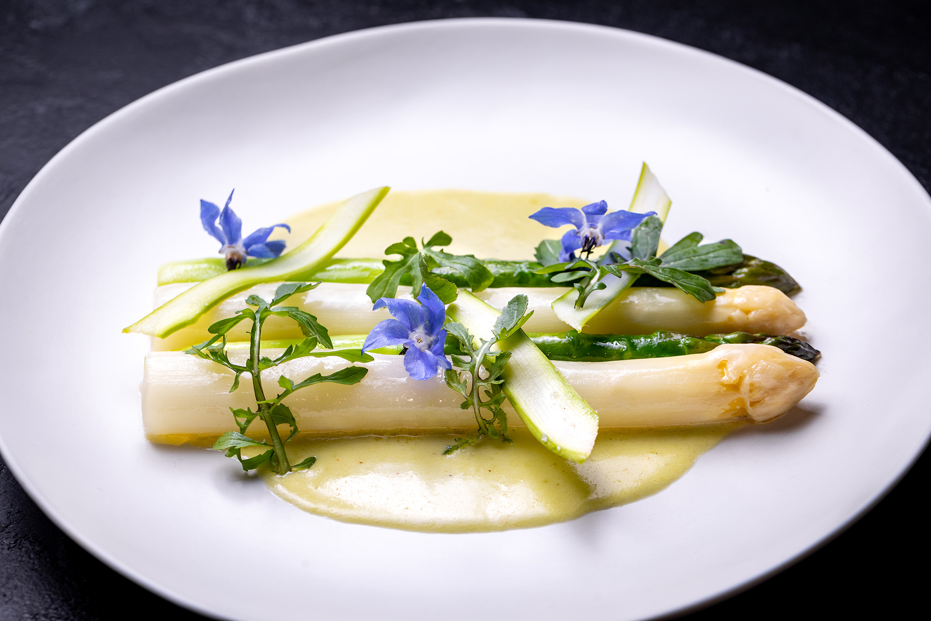 green and white asparagus topped with edible nasturtium flowers